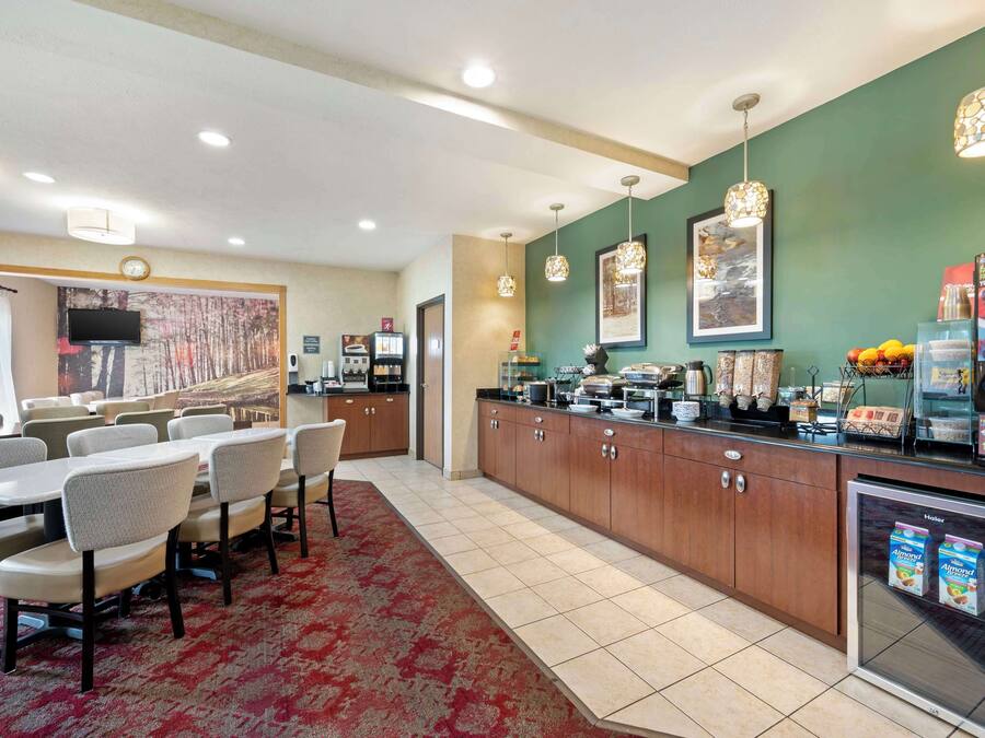 A hotel room with a dining area, a kitchenette, and a refrigerator stocked with beverages.
