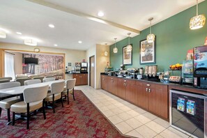 A hotel room with a dining area, a kitchenette, and a refrigerator stocked with beverages.