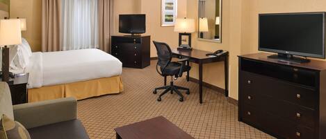 A hotel room with a bed, desk, chair, television, and a small table.
