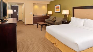 Hotelkamer met een groot bed, een bureau, een stoel, een bank, een televisie en een kitchenette.