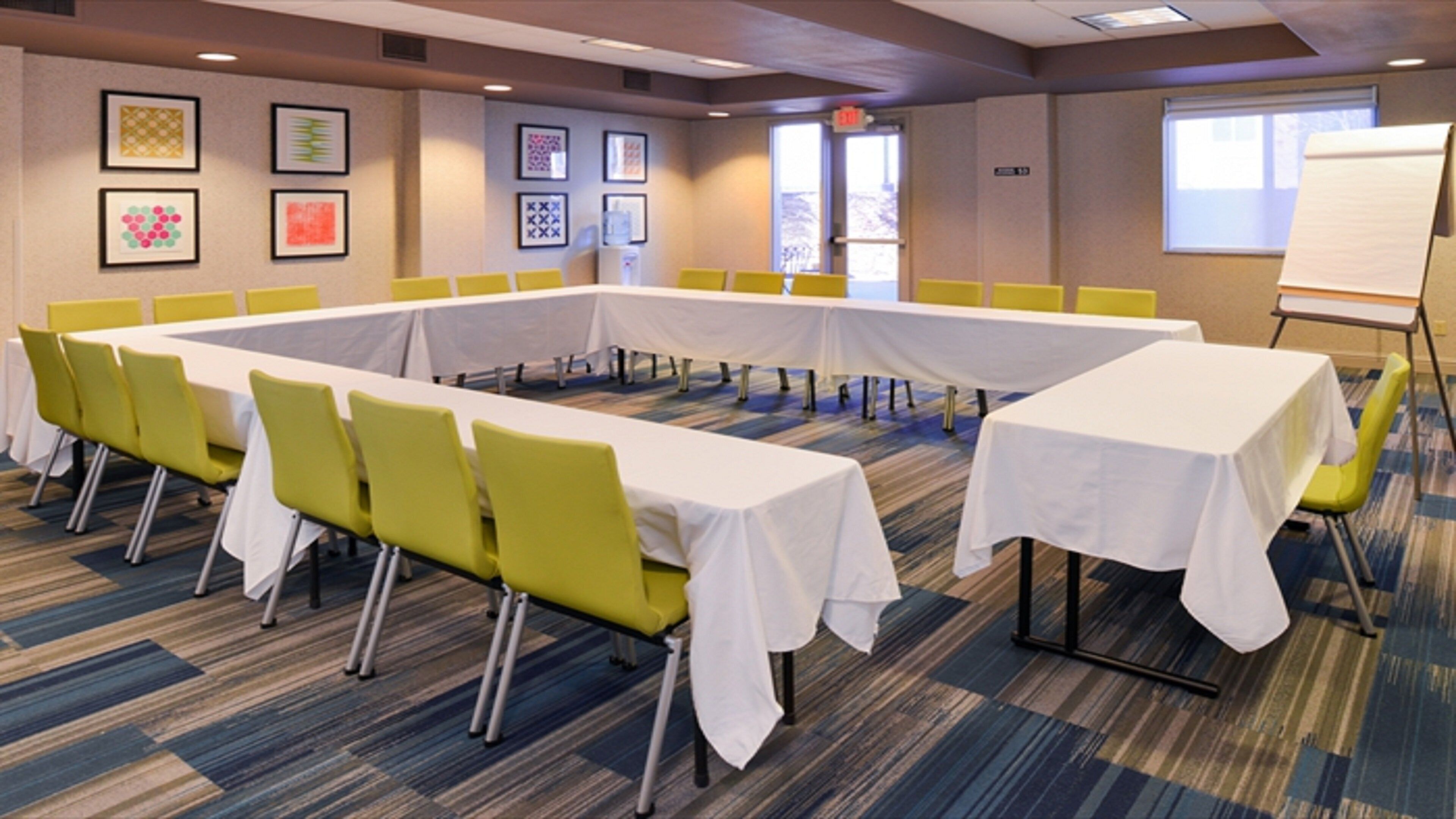 A conference room with a long table, yellow chairs, and a whiteboard.