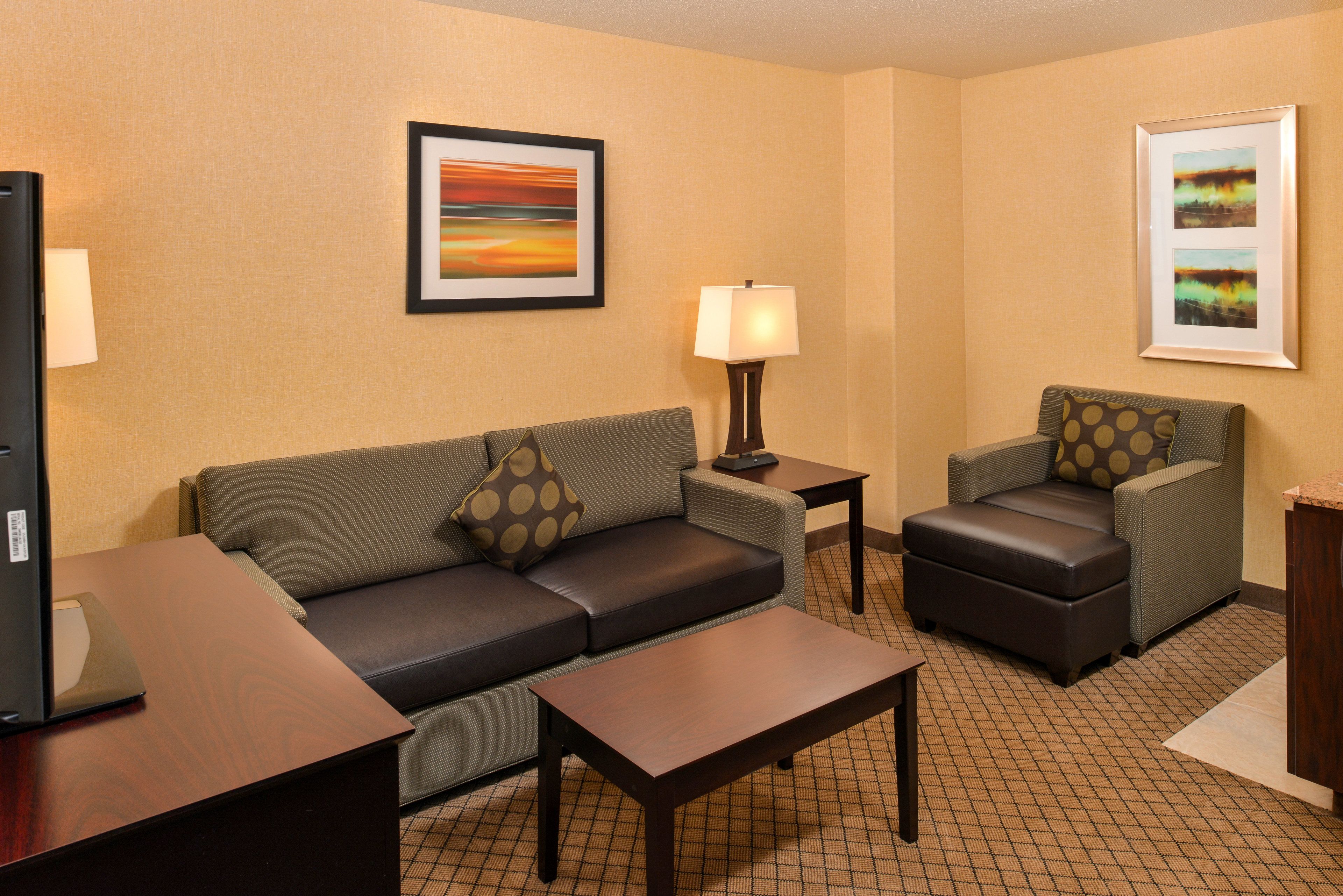 Une chambre d’hôtel avec un canapé, un fauteuil, une petite table et un téléviseur.