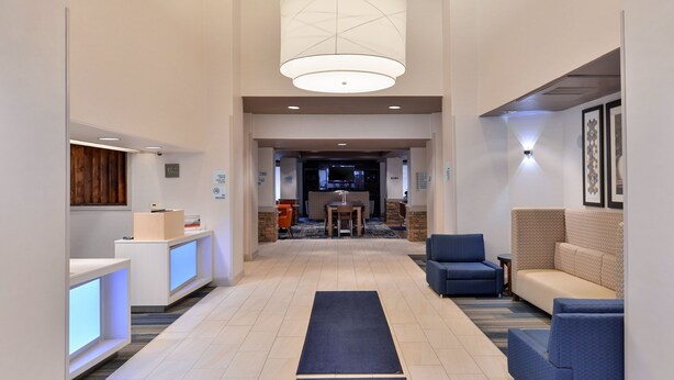 A hotel lobby with a reception desk, seating area, and a large chandelier. - Holiday Inn Express Sacramento Airport Woodland by IHG (Woodland)