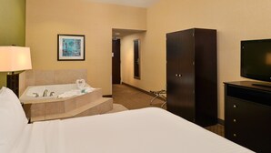 A hotel room with a bed, a desk with a lamp, a large dark cabinet, a television, and a framed picture on the wall. - Holiday Inn Express Sacramento Airport Woodland by IHG (Woodland)