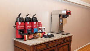 Eine Kaffeestation mit drei Kaffeemaschinen, einem Kaffeebecherhalter und einer Packung Kaffeeweißer.