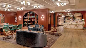 Une pièce spacieuse avec un canapé incurvé, un coin repas avec des chaises vertes et une bibliothèque.