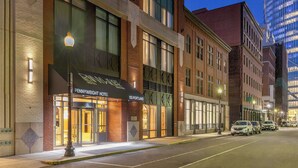 Un hôtel à la façade en briques, doté de grandes fenêtres et d’une enseigne indiquant « Pennyweight Hotel, 155 Portland ».