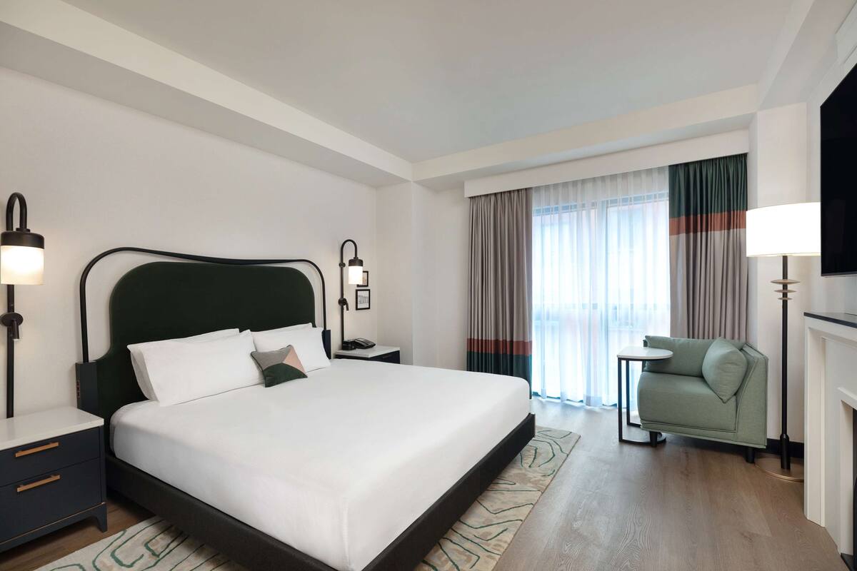 Une chambre d’hôtel moderne, dotée d’un grand lit, de tables de chevet, d’un canapé et d’une télévision.