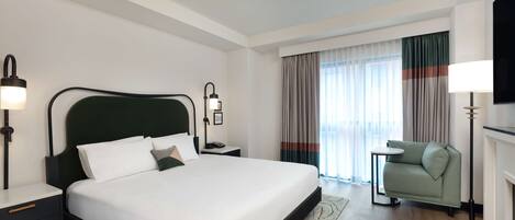 A modern hotel room with a large bed, bedside tables, a sofa, and a TV.
