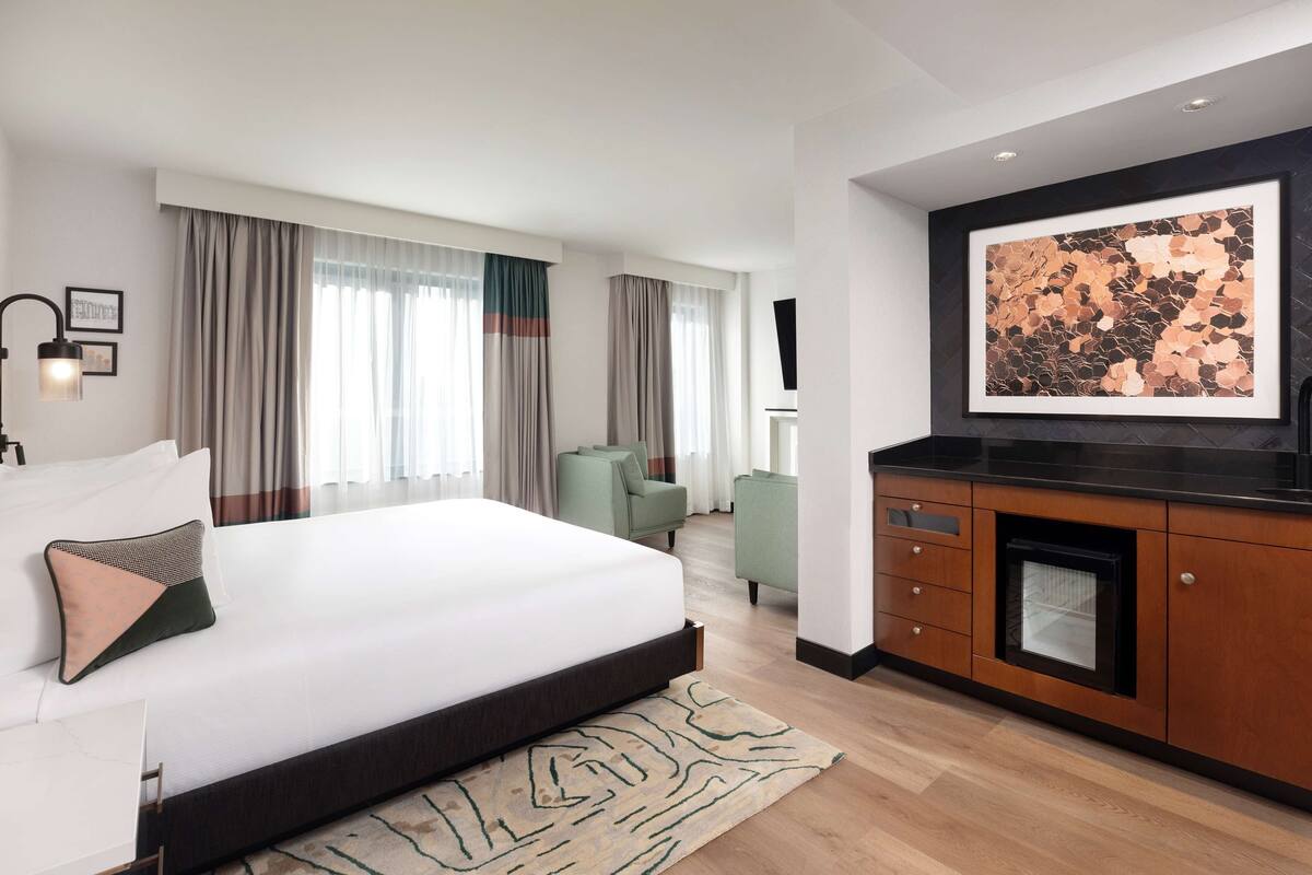 Une chambre d’hôtel moderne dotée d’un grand lit, d’un coin salon et d’un espace repas.