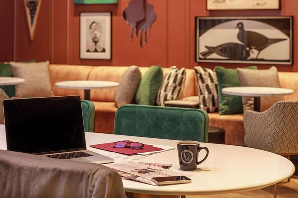 A cozy seating area with a laptop, a smartphone, a mug, and a magazine on a round table.