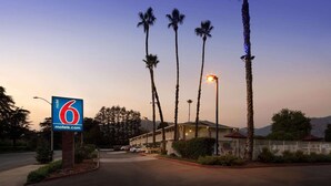 A motel with a prominent sign, tall palm trees, and a building with a light on top. - Motel 6 Arcadia, CA - Los Angeles - Pasadena Area (Arcadia)