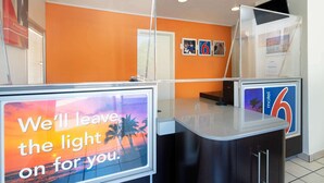 A reception area with a counter, a sign reading "We'll leave the light on for you.", and a number 6 sign indicating a motel. - Motel 6 Arcadia, CA - Los Angeles - Pasadena Area (Arcadia)