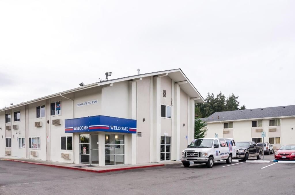 A building with a 'WELCOME' sign, a parking lot, and several vehicles.