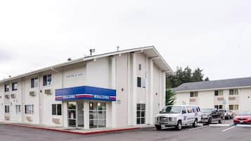 A building with a 'WELCOME' sign, a parking lot, and several vehicles.