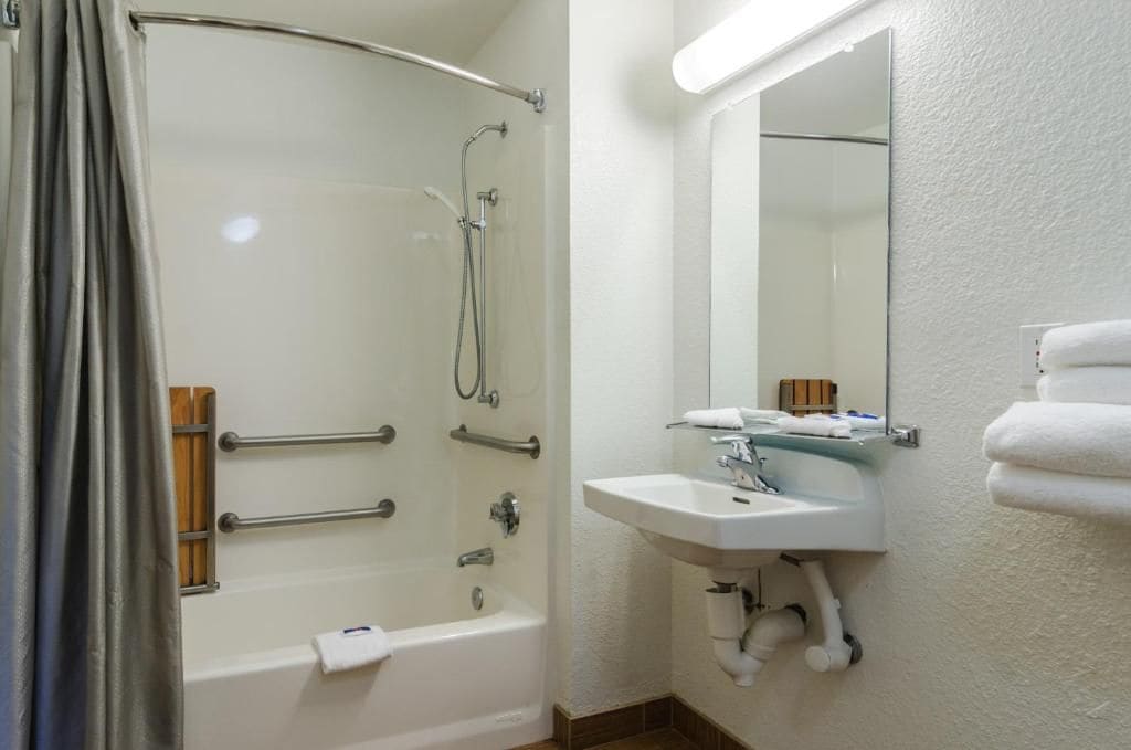 A bathroom with a bathtub, a sink, and a mirror.