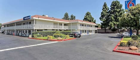 A motel with a two-story structure, a parking lot, and a clear sky.