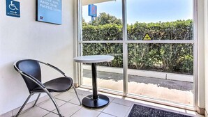 Hall d'hotel con un'insegna per accessibilità con sedia a rotelle, un tavolo e una poltrona.