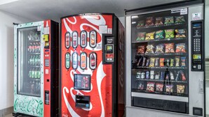 Tres máquinas expendedoras: una de Coca-Cola, una máquina con la marca Coca-Cola y una máquina de aperitivos.