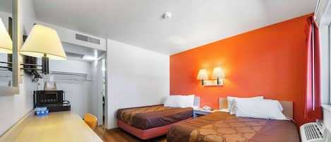A hotel room with two beds, a desk, a microwave, and a small kitchenette.