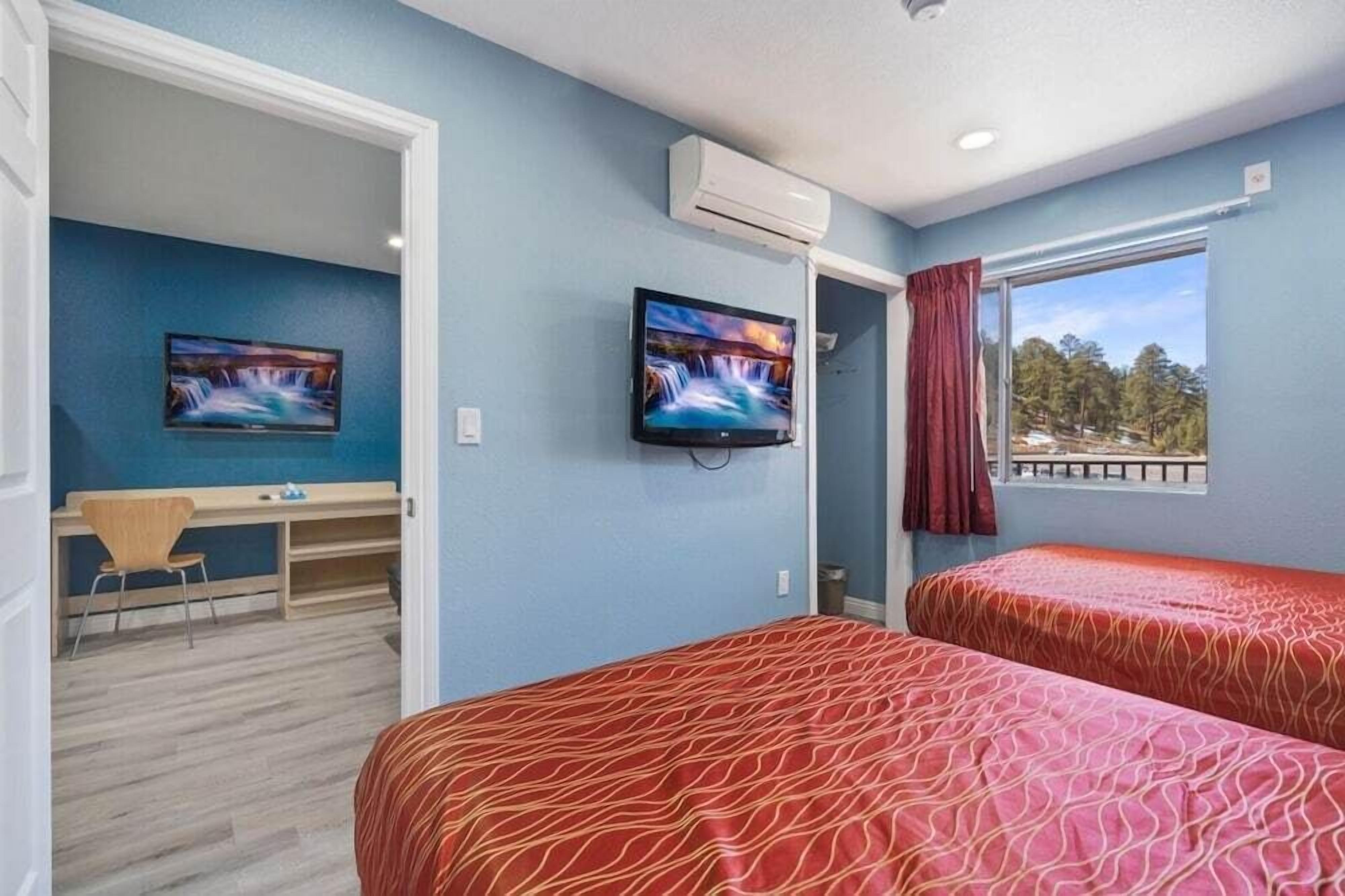 Una habitación con dos camas, un escritorio y un televisor.