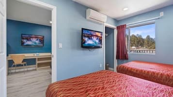 Una habitación con dos camas, un escritorio y un televisor.