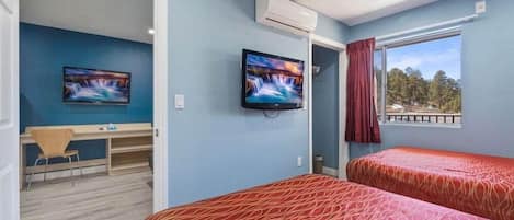 Una habitación con dos camas, un escritorio y un televisor.