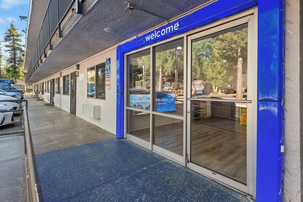 A building entrance with a 'welcome' sign, a covered parking area, and a visible handicap-accessible sign.