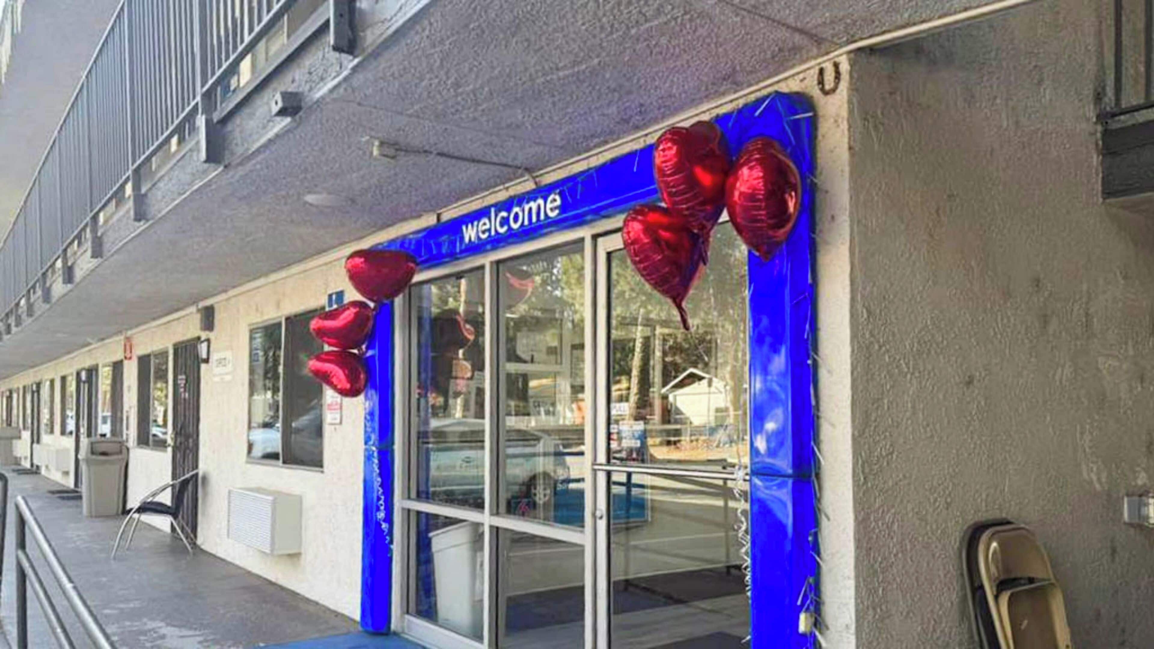 A building entrance with a 'welcome' sign and red balloons.