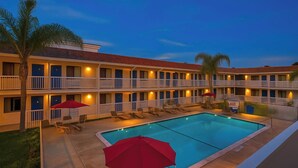 A hotel with a pool, multiple balconies, and outdoor seating areas. - Motel 6 Carlsbad, CA Beach (Carlsbad)