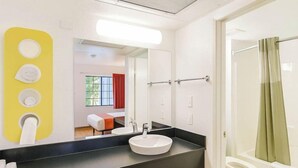 A modern bathroom with a large mirror, a sink, and a shower. - Motel 6 Carlsbad, CA Beach (Carlsbad)