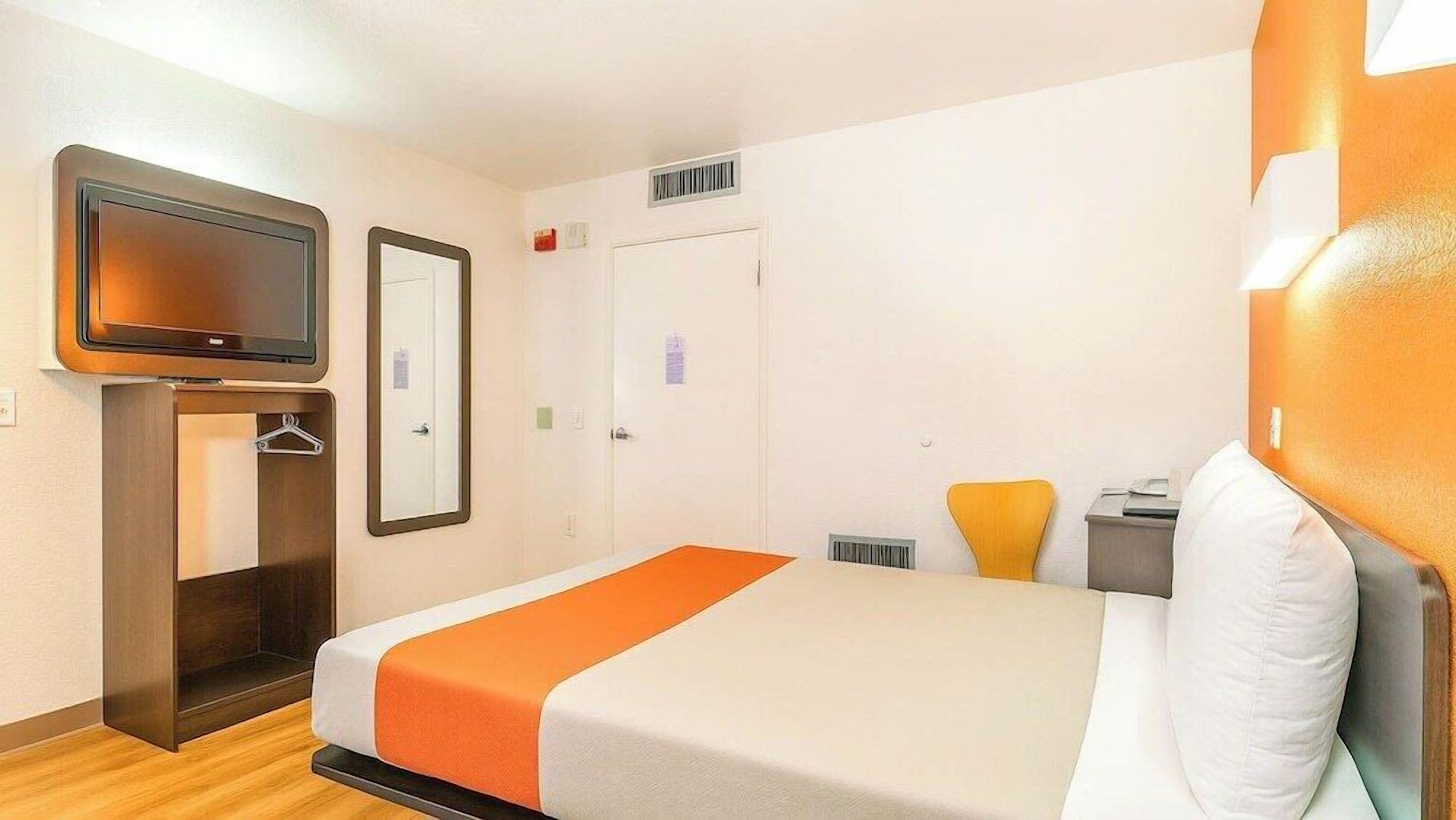 A hotel room with a bed, a TV, a wardrobe, and a door.