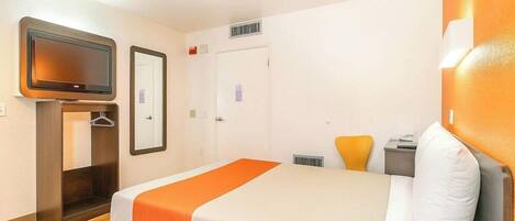 A hotel room with a bed, a TV, a wardrobe, and a door.