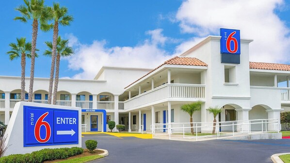 A hotel with a sign indicating '6 ENTER' and a building with multiple balconies and a red-tiled roof.