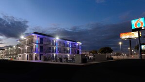 Un hôtel à plusieurs étages doté d’un balcon et d’un espace piscine, le tout éclairé par un système d’éclairage artificiel.