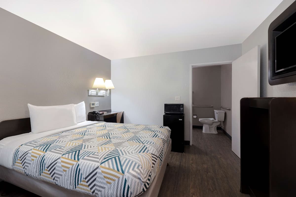 Ein Hotelzimmer mit Bett, Schreibtisch, Fernseher, Mikrowelle und Bad.