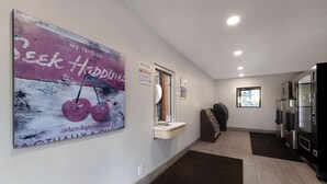 Un espace d’accueil comprenant une grande affiche, un comptoir de réception, un distributeur automatique et un réfrigérateur.