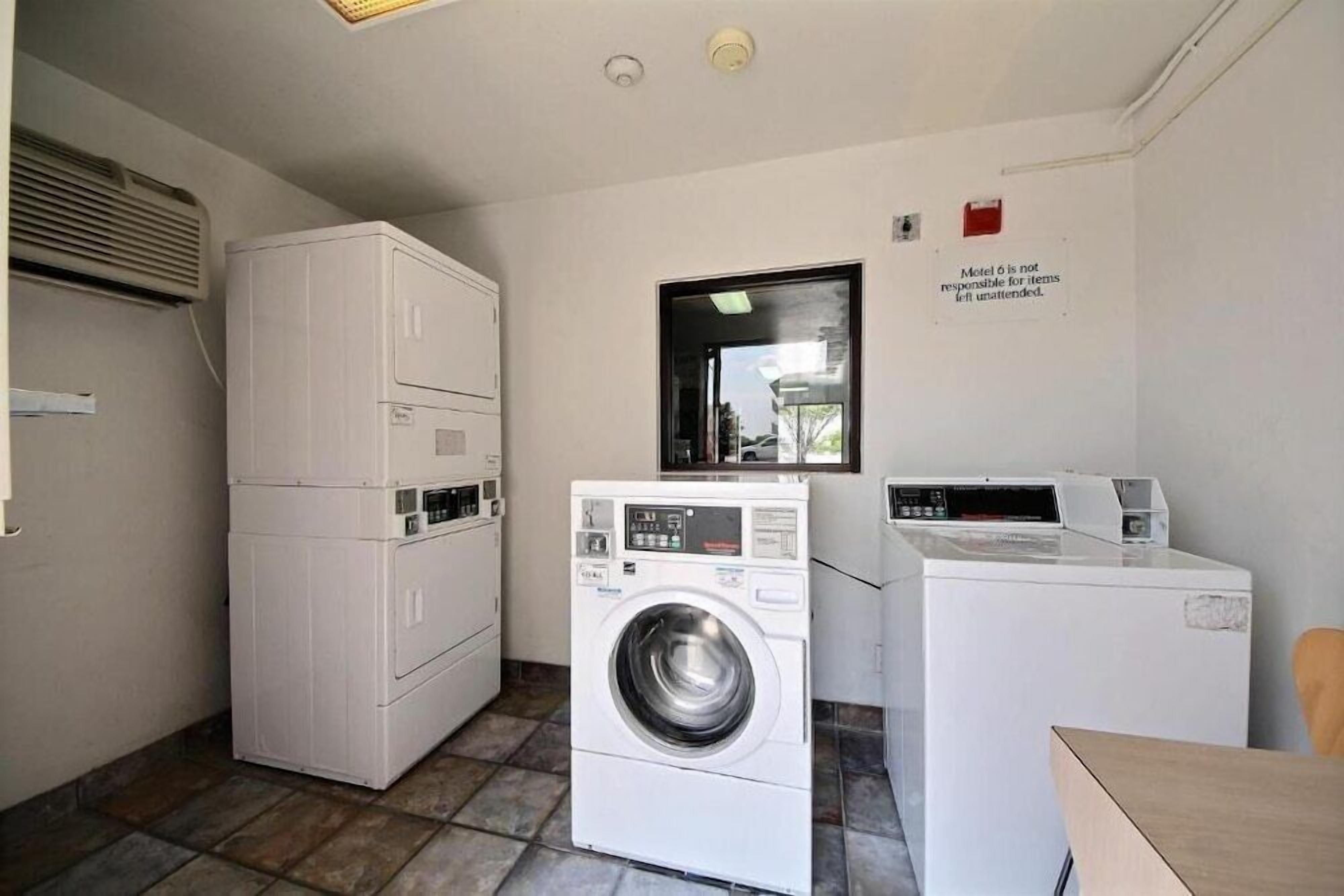 A laundry room with stacked washers and dryers, a window, and a sign stating 'Motel is not responsible for items left unattended.'