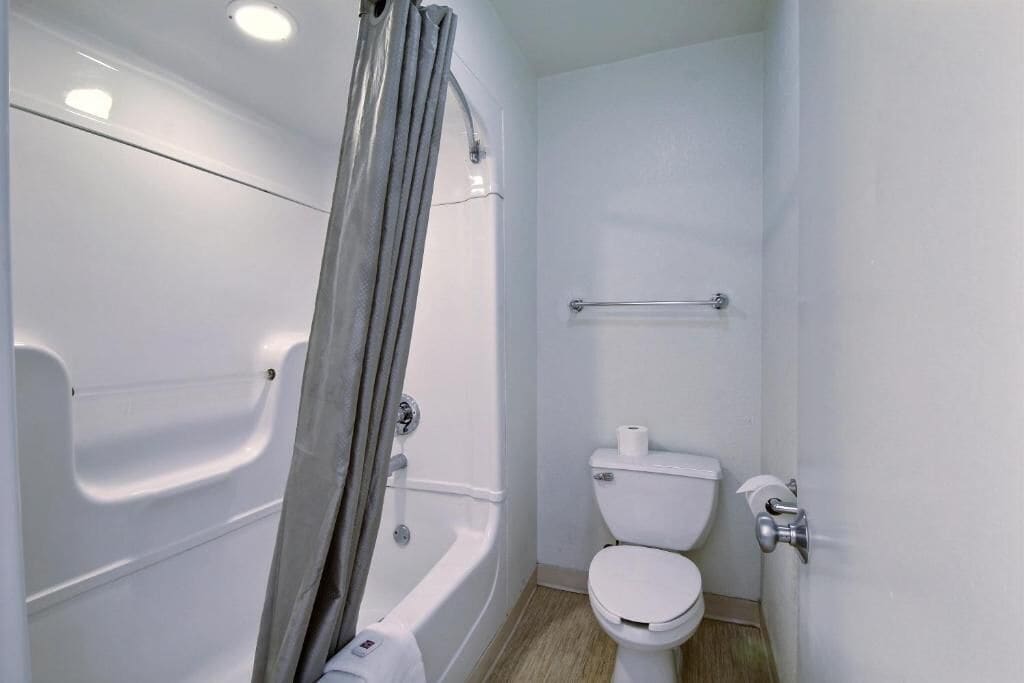 Un baño pequeño y moderno con bañera, inodoro y cortina de ducha.