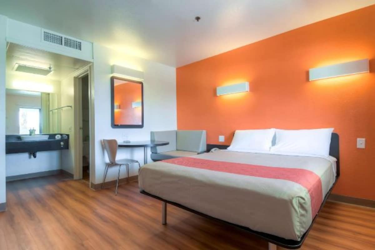 A hotel room with a bed, a desk, a chair, and a bathroom.