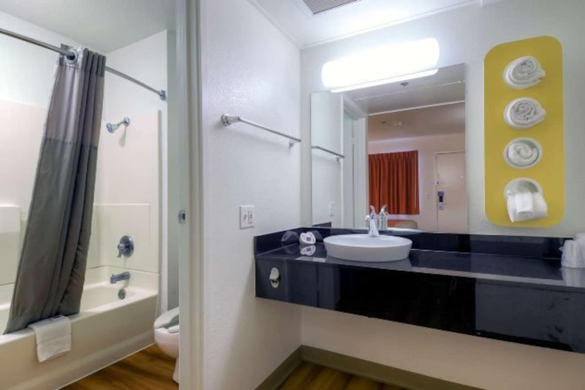 A bathroom with a bathtub, a sink, and a mirror.
