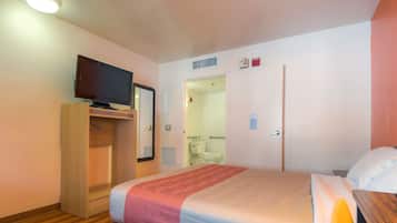 A hotel room with a bed, a TV on a stand, a wardrobe, and a bathroom visible through an open door.