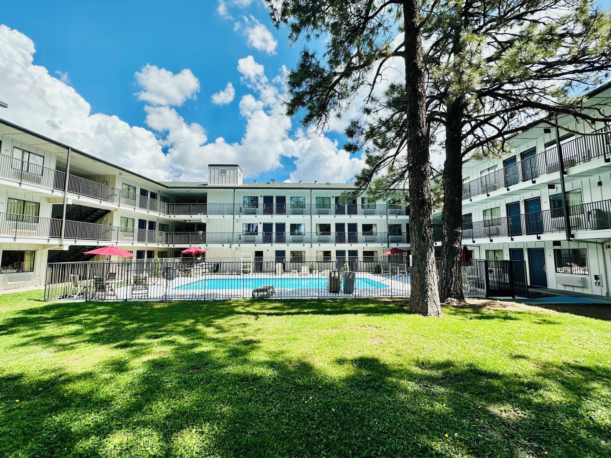 A multi-story hotel with a central courtyard featuring a swimming pool, surrounded by balconies and outdoor seating areas.