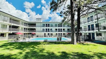 Un hôtel à plusieurs étages doté d’une cour intérieure où se trouve une piscine, le tout entouré de balcons et d’espaces de détente en plein air.