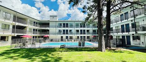 Un hôtel à plusieurs étages doté d’une cour intérieure où se trouve une piscine, le tout entouré de balcons et d’espaces de détente en plein air.