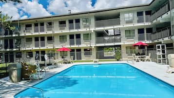 Un hôtel à plusieurs étages doté d’un espace piscine, comprenant des chaises longues et des parasols.