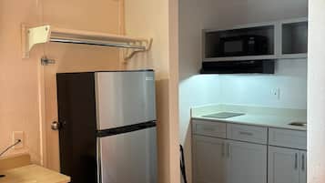 Cocina compacta con refrigerador, microondas y una pequeña encimera.