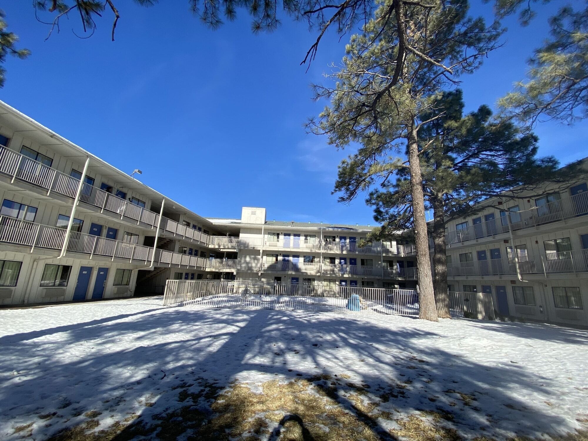 A multi-story building with balconies, a central courtyard, and a large tree.