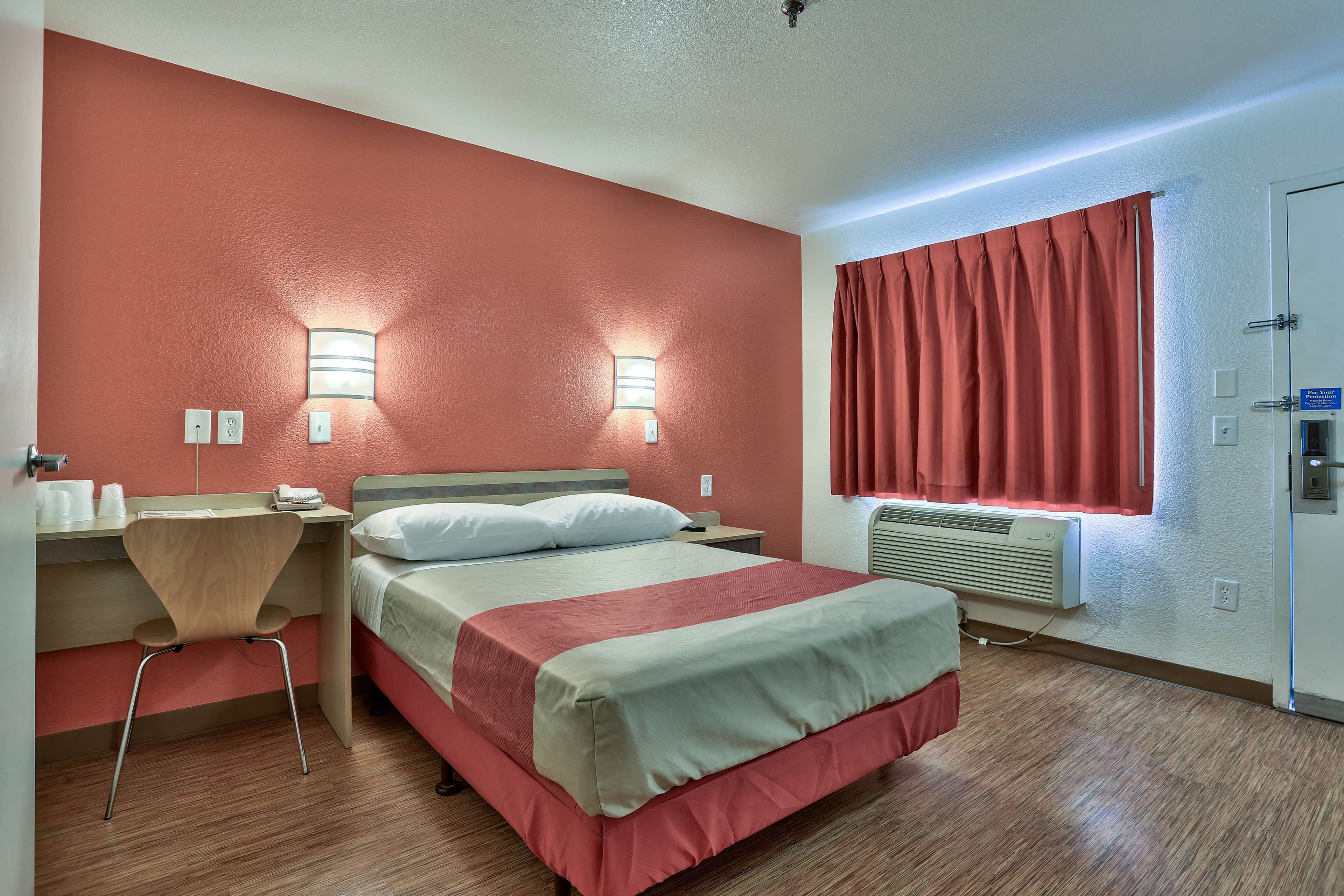 Ein Hotelzimmer mit Bett, Schreibtisch, Stuhl und zwei Wandleuchten.