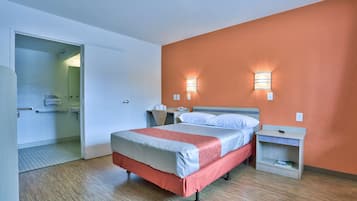 Una habitación de hotel con cama, mesitas de noche y un velador.